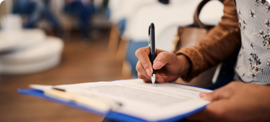 Person filling out paperwork on a clipboard