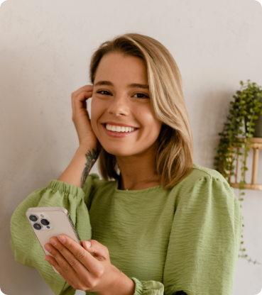 Smiling young woman in a green sweater holding her phone