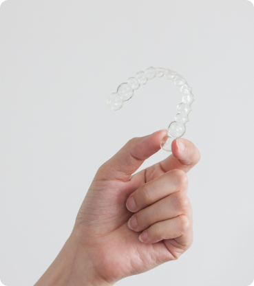 Hand holding an Invisalign clear aligner
