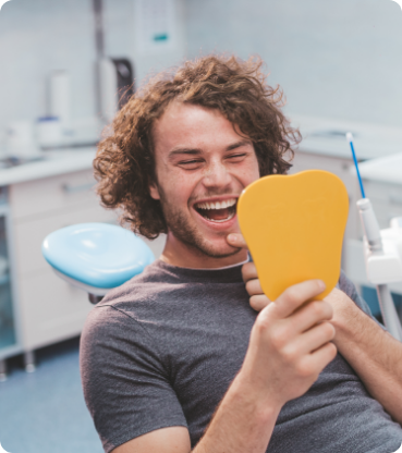 Young man in the dental chair looking at his smile in a mirror