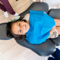Young girl in the dental chair looking up at the camera